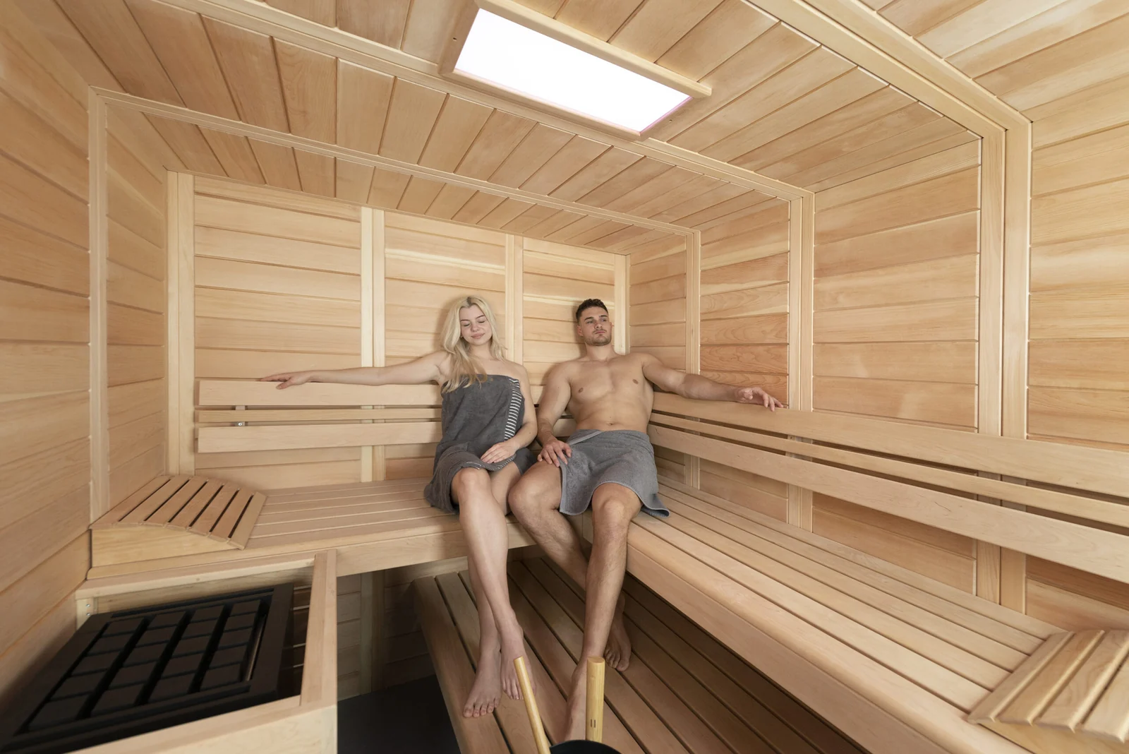 Zwei Personen auf der Bank einer hellen Sauna