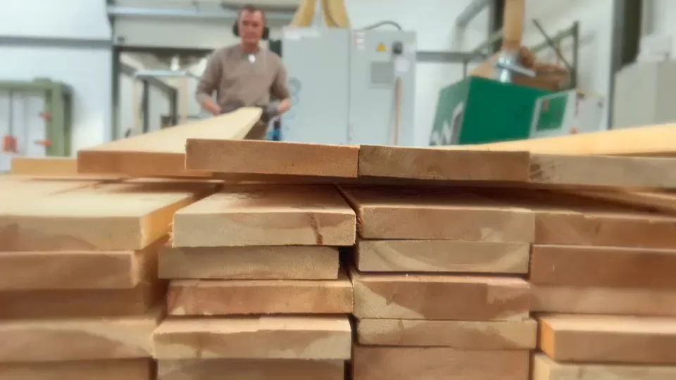 Polarholz Produktion: gestapelte Holzbohlen und Maschinen in der Werkstatt
